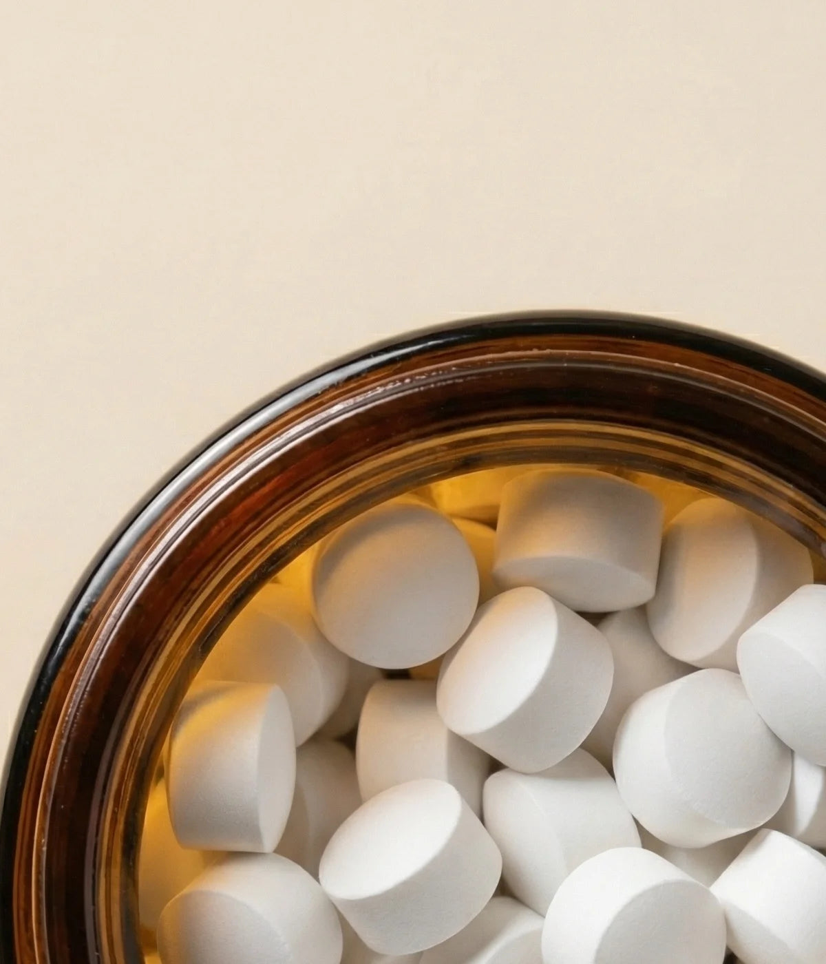 Faeora open amber brown glass jar with off white Faeora tablets on a beige background.