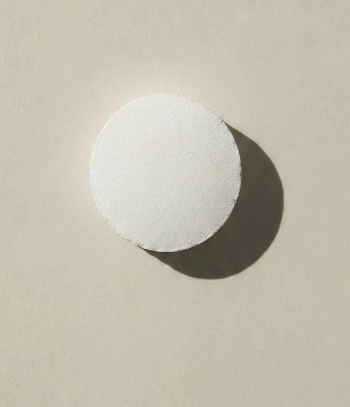 White Faeora toothpaste tablet on a beige background.