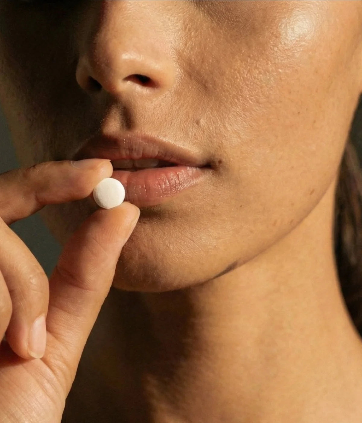 Close-up of a person holding a Faeora toothpaste tablet near her mouth.